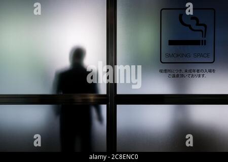 Ein Raucher in einem Raucherbereich eines Gebäudes in Roppongi, Tokio, Japan Stockfoto