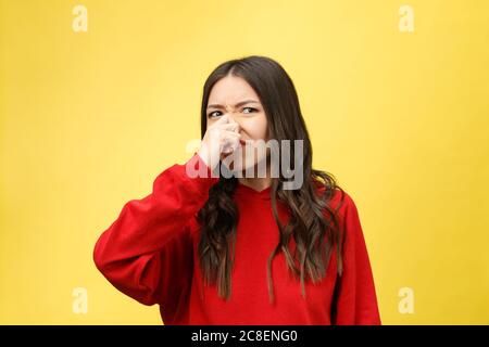 Es roch schlecht. Junge Dame macht Abstösse den Geruch isolieren auf gelbem Hintergrund. Stockfoto