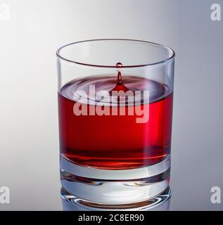 Lassen Sie den Wein aus nächster Nähe fallen. High-Speed-Aufnahme. Glas mit Rotwein. Stockfoto