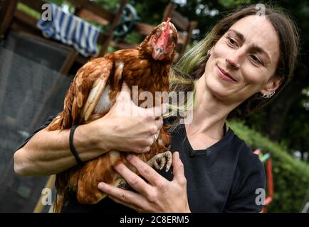 Berlin, Deutschland. Juli 2020. Hühnerbesitzerin Vanessa Janßen hat eines ihrer Hühner auf dem Arm. Im Garten von Vanessa Janßen aus Berlin-Rudow gibt es seit Sommer 2019 keine Stammhühner, die kratzen und pickten, sondern sechs Hybridhühner, Kreuzungen verschiedener Rassen mit guter Verlegeleistung. (Nach dem Urban Gardening kommen die Hühner) Quelle: Britta Pedersen/dpa-Zentralbild/dpa/Alamy Live News Stockfoto