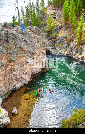 Wyoming, USA - 24. August 2019: Gruppe von Tauchern erkunden den Firehole River im Yellowstone National Park, Wyoming, USA, während ein Tourist Fotos macht Stockfoto