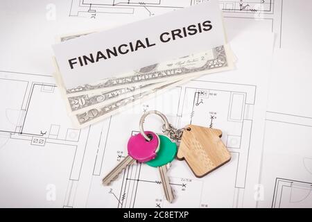 Schlüssel des Hauses, Währungen Dollar und Inschrift Finanzkrise auf Wohnplan. Konzept der Immobilienkrise durch Coronavirus verursacht Stockfoto