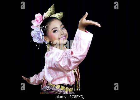 Ein isoliertes Bild mit schwarzem Hintergrund eines asiatischen Mädchens, das in traditionellen Kostümen im Norden Thailands gekleidet ist und traditionellen Tanz aufführt. Stockfoto