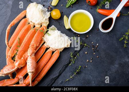 Frische Krabbenkrallen, Limette, Gewürze, Gewürze, Eis, Garnelen, Gemüse auf dunklem Hintergrund. Köstliche Meeresfrüchte, gesunde Ernährung Diät-Inhalt Stockfoto