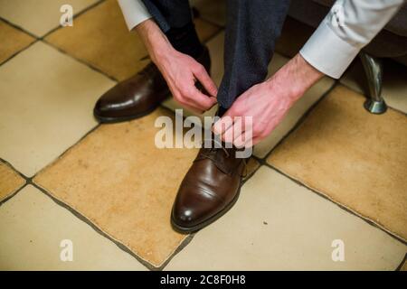 Ein Mann bindet die Schnürsenkel an braune Schuhe Stockfoto