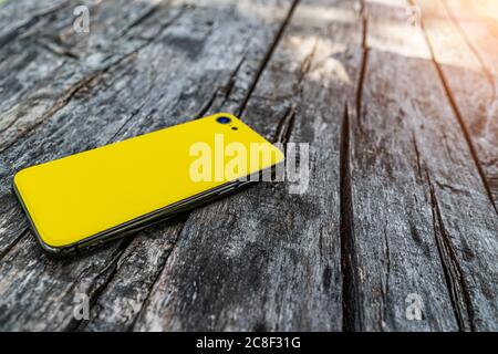 Das gelbe Smartphone ist auf dem Hintergrund von Holzbrettern. Stockfoto