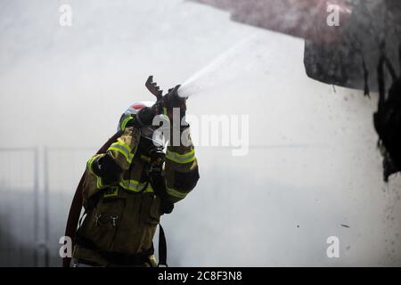 Ein Feuerwehrmann in schwerer Ausrüstung gesehen, während das Feuer löschen. Die Freiwillige Feuerwehr auf dem Gelände der man Trucks Fabrik führt die Unverwahrend Stockfoto