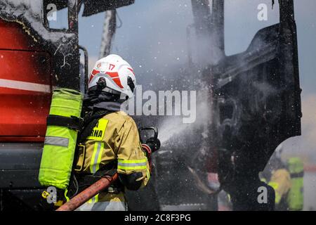 Ein Feuerwehrmann in schwerer Ausrüstung gesehen, während das Feuer in einer Kabine eines LKW. Die Freiwillige Feuerwehr auf dem Gelände der man Trucks Stockfoto