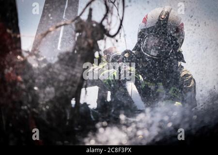 Ein Feuerwehrmann in schwerer Ausrüstung gesehen, während das Feuer in einer Kabine eines LKW. Die Freiwillige Feuerwehr auf dem Gelände der man Trucks Stockfoto