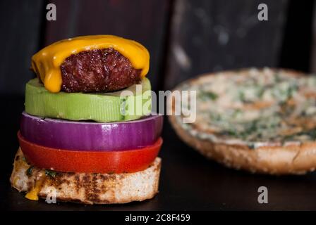 Avocado Burger mit roter Zwiebelscheibe, Burger Bun und Tomate auf einem Holzhintergrund Stockfoto