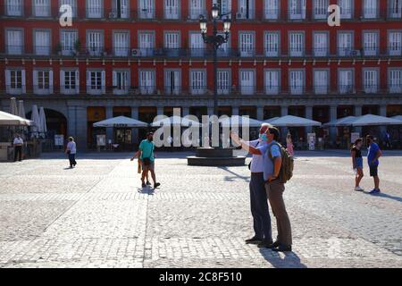 23. Juli 2020, Plaza Mayor, Madrid, Spanien: 2 Touristen mit Gesichtsmasken machen ein Selfie auf der Plaza Mayor / Great Square. Seit dem 21. Juni hat Spanien die Reisebeschränkungen nach einer strengen Sperre zur Kontrolle des Covid 19-Coronavirus gelockert, und die europäischen Länder haben Grenzen geöffnet und Flugbrücken koordiniert, um Reisen und Tourismus zu ermöglichen, die wirtschaftlichen Auswirkungen des Virus zu reduzieren. Spanien ist eines der meistbesuchten Länder der Welt und der Tourismus ist ein wichtiger Beitrag zur spanischen Wirtschaft. Die Plaza Mayor ist eine der Hauptattraktionen Madrids und ist normalerweise voller Menschen und Touristen Stockfoto