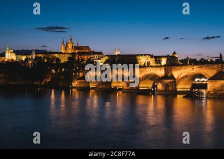 Karlsbrücke in Prag bei Nacht über die Moldau mit dem Veitsdom und dem Stadtbild der Prager Burg Stockfoto