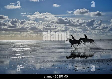 Cuxhaven, Deutschland. Juli 2020. 21.07.2020, Cuxhaven - Sahlenburg, die Ebbe an der Nordsee lockt Reiter ins Wattenmeer, die in den Sonnenuntergang reiten. Deutschland bietet auch schöne Urlaubsregionen zum Entspannen. Quelle: dpa/Alamy Live News Stockfoto