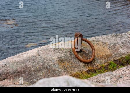 Ein alter, rostiger Metallfestungsring auf einer Klippe. Stockfoto