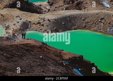 Touristen posieren für ein Foto über den Emerald Lakes (Ngā Rotopounamu) am Tongariro Alpine Crossing, Neuseeland Stockfoto