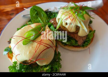Ein veganes benedict-Frühstück: In einem Restaurant mit Pflanzenbasis werden Fleisch, Haschebraun und Sauce Hollandaise auf Grünkohl und einem englischen Muffin serviert Stockfoto