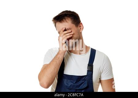 Traurige kaukasische Arbeiter-Werkstatt in blauen Overalls isoliert auf weißem Studiohintergrund. Stockfoto