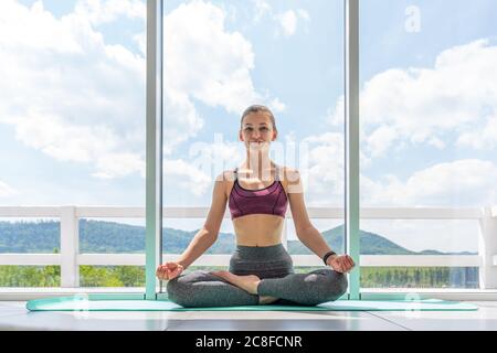 Yoga zu Hause. Ruhe bewahren. Attraktive junge Frau sitzt auf Lotusposition auf dem Boden Stockfoto