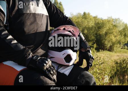 Nahaufnahme von nicht erkennbaren Motorradfahrer in Schutzhandschuhen mit Helm im Wald sitzen Stockfoto