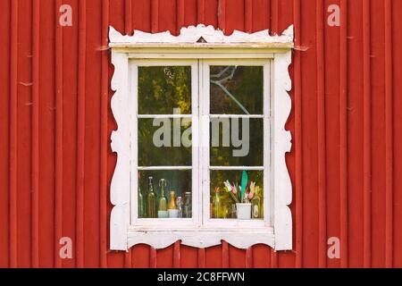 Altes verwittertes weißes Fenster in einem roten schwedischen Holzhaus Stockfoto