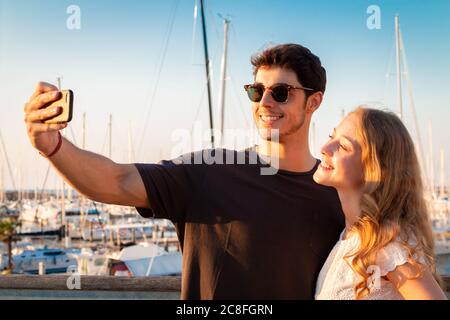 Junges Paar tahe Selfie im Abendlicht - zwei junge Touristen machen Selfie in einem Touristenhafen Stockfoto