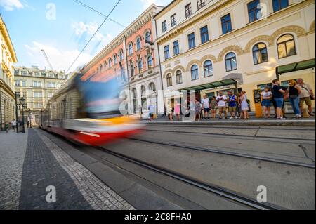 PRAG - 20. JULI 2019: Straßenbahn mit Bewegung verschwimmen vorbei wartenden Passanten an einer Straßenbahnhaltestelle in der Altstadt von Prag Stockfoto