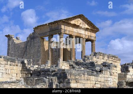 Capitol an den römischen Ruinen in Dougga, Tunesien, Nordafrika gegen einen blau bewölkten Himmel Stockfoto