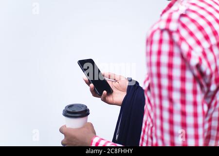 Männchen in einem rot-weiß karierten Hemd mit einem Smartphone und Kaffee auf weißem Hintergrund Stockfoto