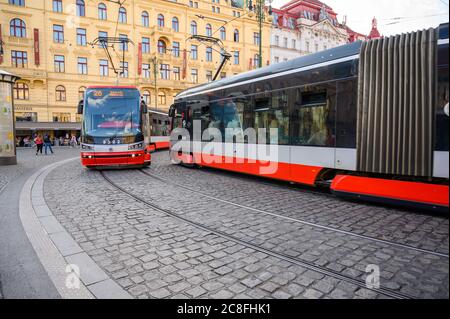 PRAG - 20. JULI 2019: Zwei moderne elektrische Straßenbahnen, die sich an einer Ecke auf den gepflasterten Straßen der Prager Altstadt vorbeifahren Stockfoto