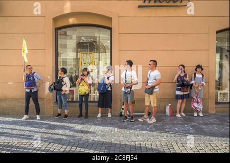 PRAG - 20. JULI 2019: Asiatische Touristen Reihen sich hinter einer Flagge mit Reiseführer auf den gepflasterten Straßen der Altstadt von Prag, Tschechische Repu Stockfoto