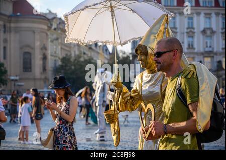 PRAG - 20. JULI 2019: Goldene weibliche Statue Street Performer posiert mit einem männlichen Touristen auf dem Altstädter Ring, Prag, Tschechische Republik Stockfoto