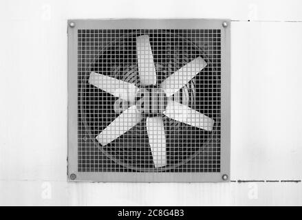 Ventilator hinter Gitter. Vorrichtung zur Regelung von Wärme und Wind. Die Rotorblätter des Belüftungssystems sind weiß. Schwarz-Weiß-Aufnahme Stockfoto