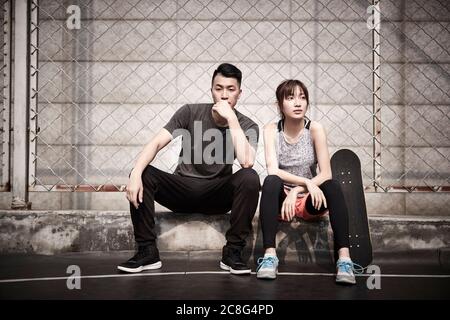 Junge asiatische Erwachsene Mann und Frau entspannen im Freien nach dem Training Stockfoto