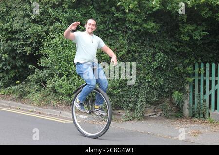 Mann auf einem Einrad winkt, wie er vorbei geht Stockfoto