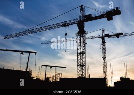 Baukräne auf der Baustelle während Sonnenuntergang Stockfoto