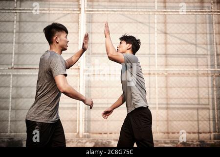 Zwei junge asiatische Athleten hallo-five feiern Erfolg Stockfoto