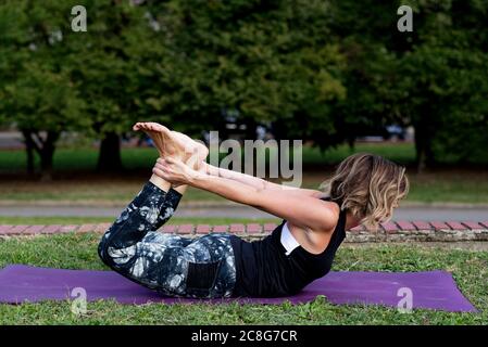 Reife blonde Frau macht Yoga in einem Park. Stockfoto