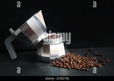 Kaffee in einer Mokakakanne mit Kaffeebohnen und gemahlenem Kaffee auf dunklem Hintergrund. Stockfoto
