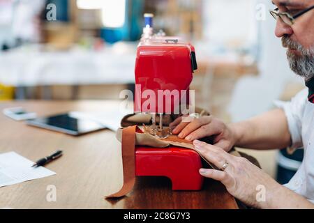 Mann mit Nähmaschine im Kreativstudio Stockfoto