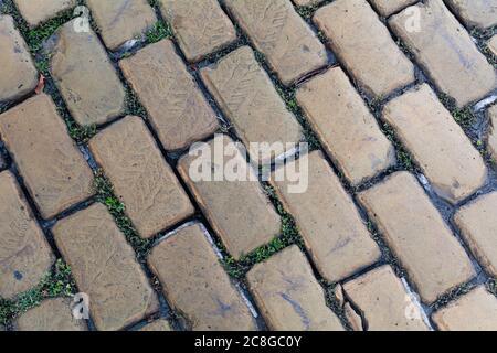 Blick von oben auf gepflasterte nasse Steinstraße. Alte Gehwege aus Granit. Straße Kopfsteinpflaster Bürgersteig in Odessa. Abstrakter Hintergrund für Design. Stockfoto