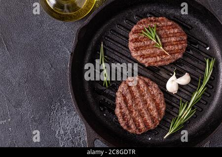 Gebratenes Schnitzel für Burger mit Gewürzen auf Grillpfanne, Draufsicht, Kopierraum. Stockfoto