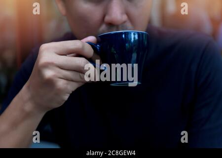 Nahaufnahme Hand Mann hält Kaffeetasse im Café, Mann entspannen mit Kaffee Kaffee nach der Arbeit Business trinken Konzept. Stockfoto