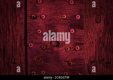 Textur aus dunklem Burgunderholz mit alten Gewindebohrschrauben. Textur von altem getrocknetem Sperrholz. Mahagoni Hintergrund für Design. Stockfoto