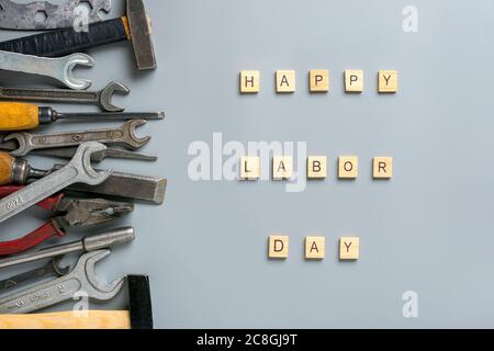 Happy Labor Day Konzept Baugruppe Heimwerkzeuge - Hammer, Säge, Schraubendreher, Meter, Zange, Schlüssel, Meißel auf grauem Hintergrund Holiday Card Top Stockfoto