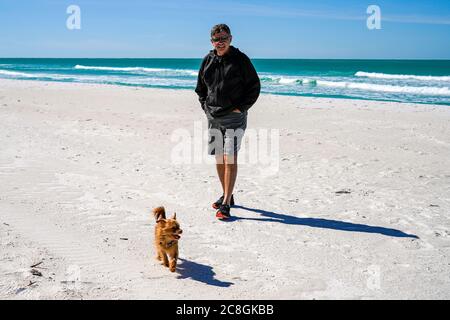 Mann und Hund gehen zu einem Strandspaziergang Stockfoto