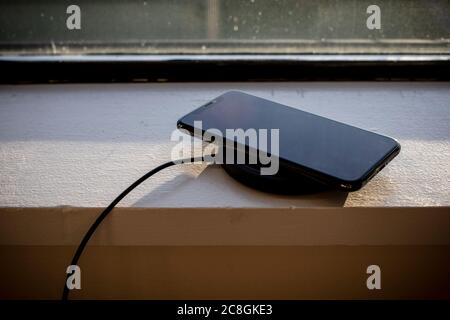 Ein Smartphone wird über ein kabelloses Ladegerät aufgeladen. Stockfoto