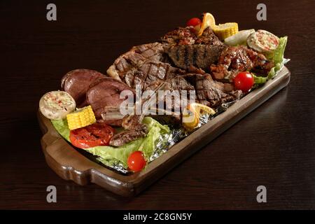 Fleisch Auswahl von Grillfleisch mit Gemüse auf einem rustikalen Tablett und Holztisch Stockfoto