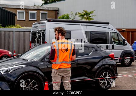 Ein Mitarbeiter, der während der Tests eine Weste mit einer sozialen Distanzierung trägt.Mitarbeiter der GGD Rotterdam führen Durchlauftests an Personen durch, die Beschwerden haben, die mit dem Coronavirus in Verbindung stehen oder vermuten, infiziert zu sein. Die Ergebnisse können die getesteten Personen innerhalb von 2 Tagen telefonisch erhalten. Stockfoto