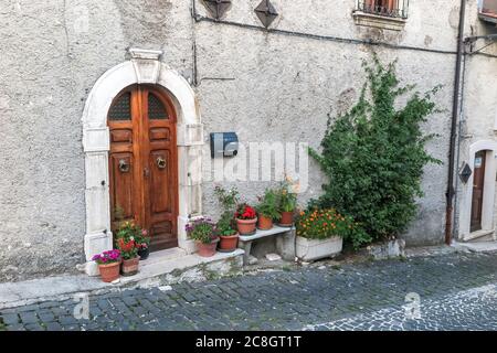 Alte Holztür am Eingang eines mittelalterlichen italienischen Hauses, mit mehreren Blumentöpfen, OPI Gemeinde, Abruzzen Region, Aquila Provinz, Italien Stockfoto