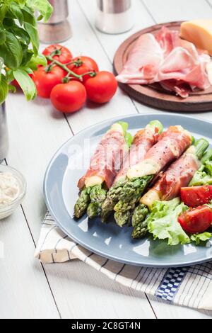 Gebackener Schinken und Käse eingewickelter Spargel mit Salat serviert Stockfoto